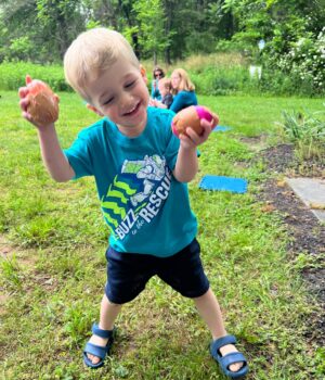 Boy playing custom-created egg shakers during outdoor music class